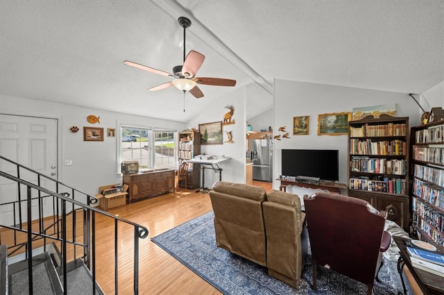 living room with ceiling fan, vaulted ceiling with beams, a textured ceiling, and hardwood / wood-style floors