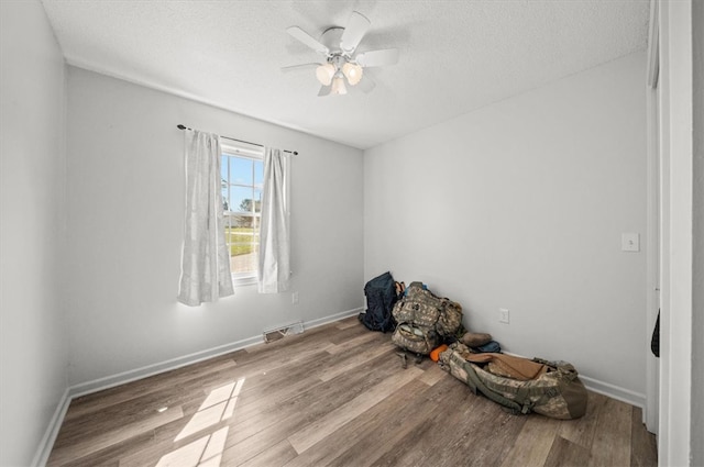 empty room featuring ceiling fan, light hardwood / wood-style floors, and a textured ceiling