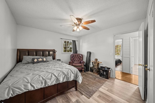 bedroom with light hardwood / wood-style floors, a textured ceiling, and ceiling fan