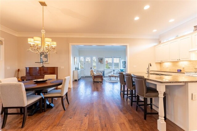 dining area with crown molding, dark hardwood / wood-style floors, a chandelier, and sink