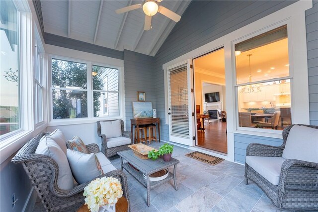 sunroom / solarium featuring ceiling fan with notable chandelier and lofted ceiling with beams