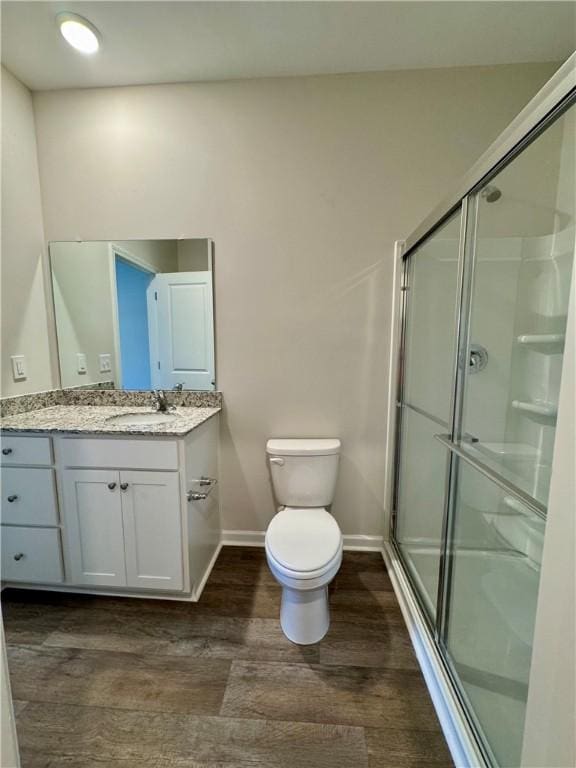 bathroom with hardwood / wood-style flooring, vanity, toilet, and an enclosed shower