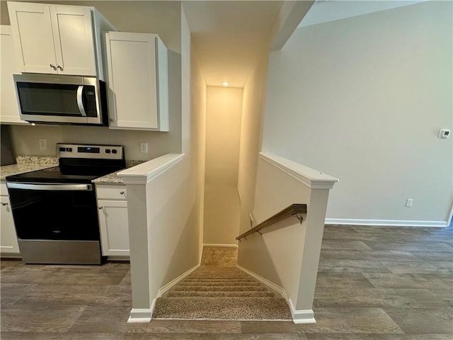 kitchen featuring white cabinets, light hardwood / wood-style floors, light stone countertops, and stainless steel appliances