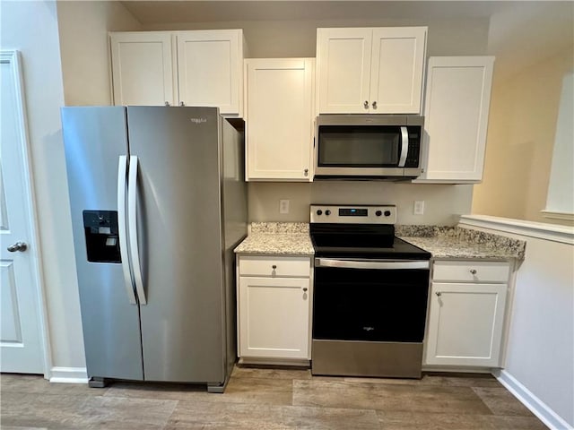 kitchen with white cabinets, stainless steel appliances, and light stone countertops