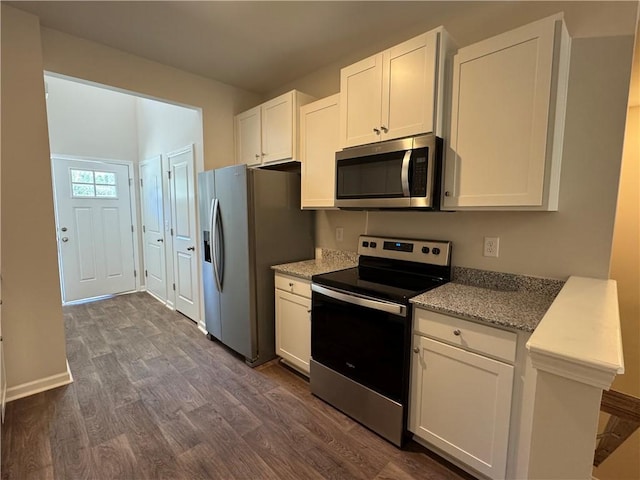 kitchen featuring light stone counters, dark wood-type flooring, stainless steel appliances, and white cabinets