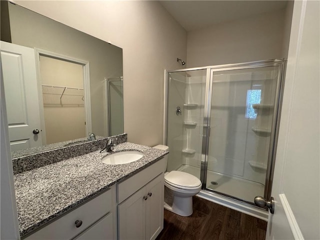 bathroom with vanity, a shower with shower door, hardwood / wood-style floors, and toilet