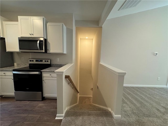 kitchen featuring dark carpet, stainless steel appliances, and white cabinetry