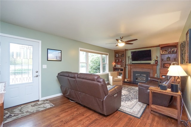 living room with ceiling fan, wood-type flooring, and a fireplace