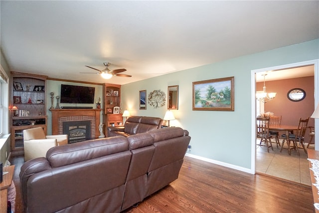 living room featuring a fireplace, ceiling fan with notable chandelier, and dark hardwood / wood-style floors