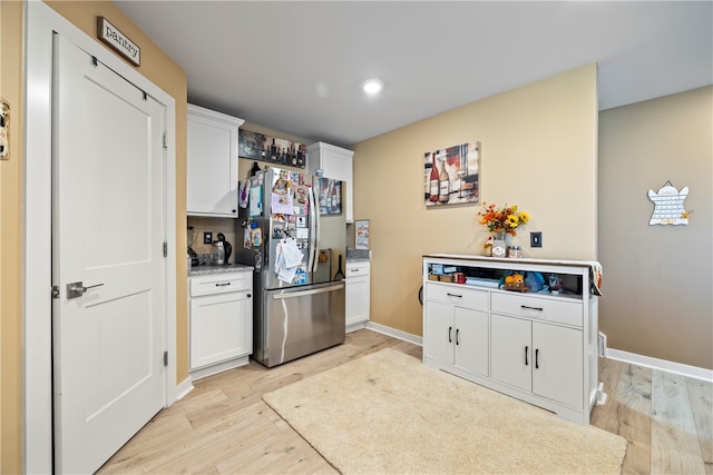 kitchen featuring stainless steel refrigerator, light hardwood / wood-style flooring, and white cabinetry