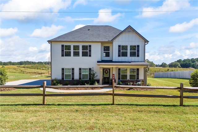 view of front facade with a rural view, a porch, and a front yard