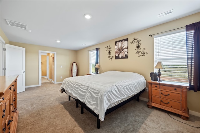 bedroom with ensuite bath, multiple windows, and light carpet