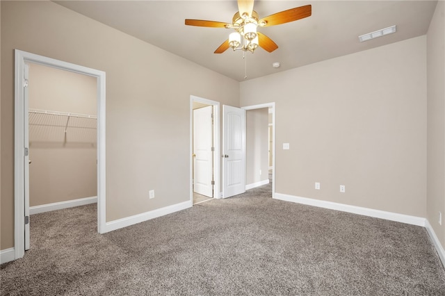 unfurnished bedroom featuring carpet floors, a walk in closet, visible vents, and baseboards