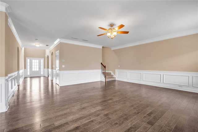 unfurnished room featuring ceiling fan, stairway, a decorative wall, and dark wood-type flooring