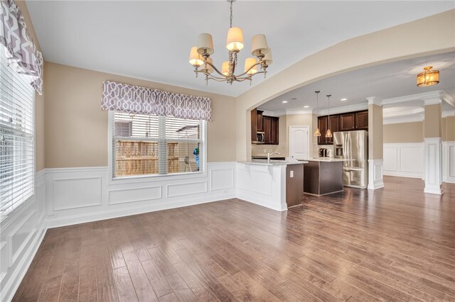 unfurnished living room with recessed lighting, dark wood-type flooring, wainscoting, a sink, and a chandelier