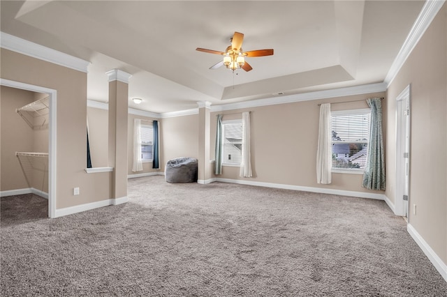 interior space with ceiling fan, baseboards, ornamental molding, a tray ceiling, and ornate columns