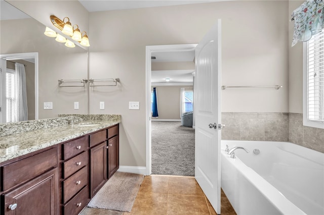 bathroom featuring tile patterned flooring, a garden tub, vanity, and a healthy amount of sunlight