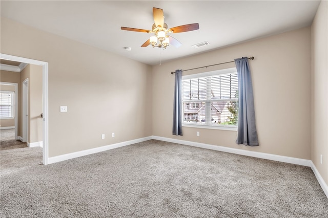 spare room with carpet floors, a wealth of natural light, visible vents, and baseboards