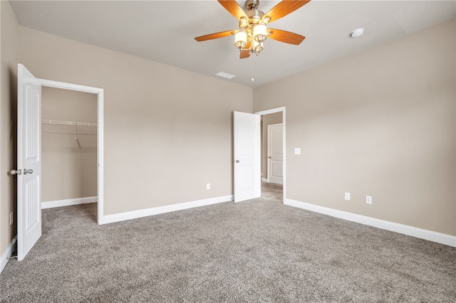 unfurnished bedroom featuring carpet floors, a walk in closet, visible vents, and baseboards