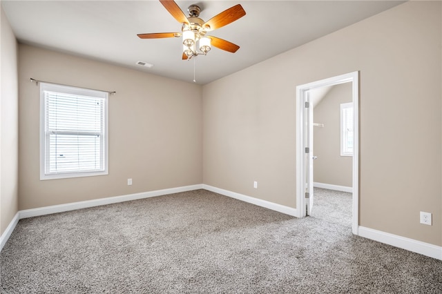 empty room featuring carpet floors, baseboards, visible vents, and a ceiling fan