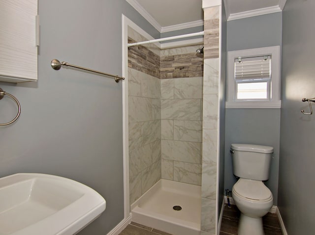 bathroom featuring a tile shower, crown molding, and toilet