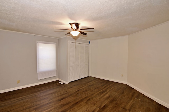 unfurnished bedroom with ceiling fan, a closet, dark hardwood / wood-style flooring, crown molding, and a textured ceiling