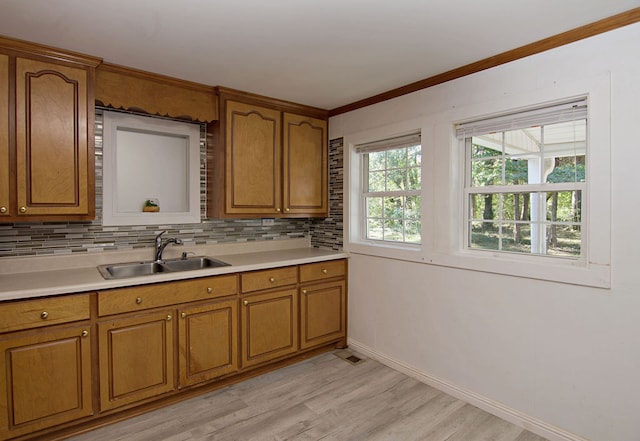 kitchen featuring backsplash, crown molding, sink, and light hardwood / wood-style flooring