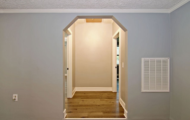 corridor featuring hardwood / wood-style flooring, ornamental molding, and a textured ceiling