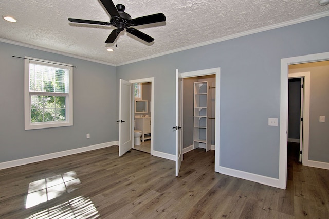 unfurnished bedroom featuring ceiling fan, ornamental molding, ensuite bathroom, and dark wood-type flooring