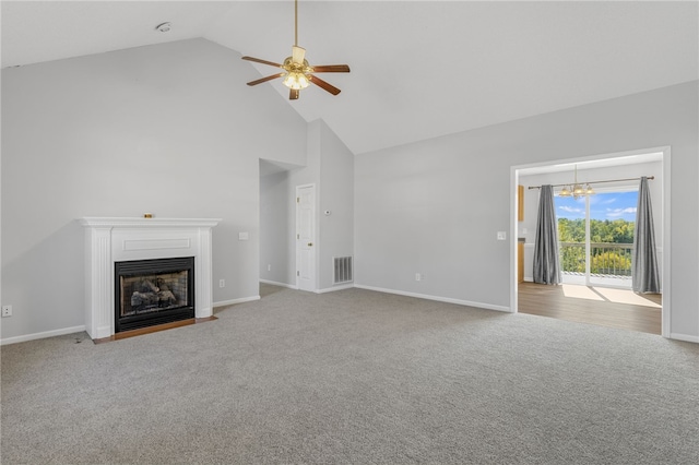 unfurnished living room featuring ceiling fan with notable chandelier, light colored carpet, and high vaulted ceiling