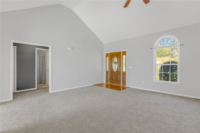 unfurnished bedroom featuring ensuite bath, light carpet, ceiling fan, and high vaulted ceiling