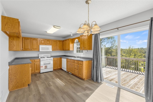 kitchen with pendant lighting, white appliances, sink, wood-type flooring, and a chandelier