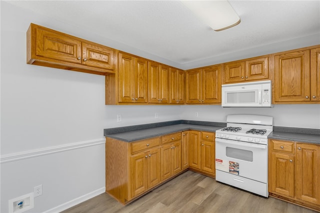 kitchen with white appliances and light hardwood / wood-style floors