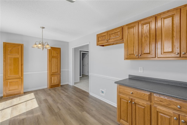 kitchen with pendant lighting, a textured ceiling, light hardwood / wood-style flooring, and a notable chandelier