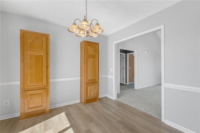 spare room featuring light wood-type flooring and an inviting chandelier