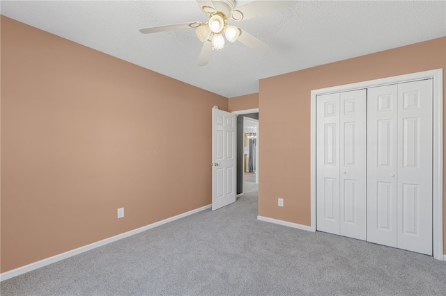 unfurnished bedroom featuring light carpet, a textured ceiling, a closet, and ceiling fan