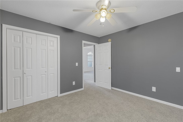 unfurnished bedroom with ceiling fan, light colored carpet, a textured ceiling, and a closet