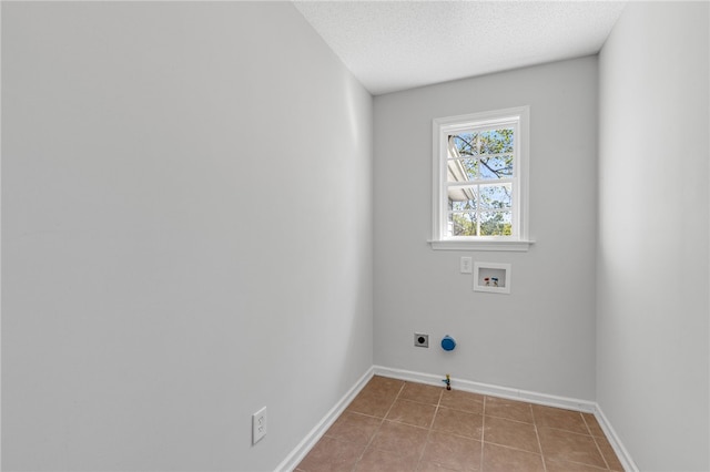 clothes washing area with electric dryer hookup, hookup for a gas dryer, hookup for a washing machine, a textured ceiling, and light tile patterned floors