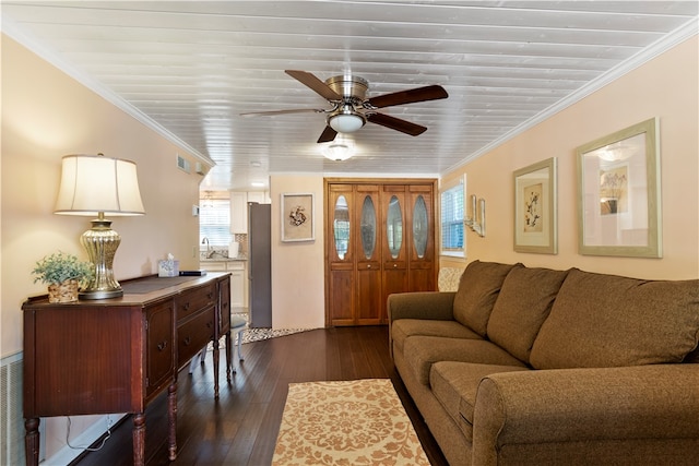 living room with ornamental molding, dark wood-type flooring, and a ceiling fan