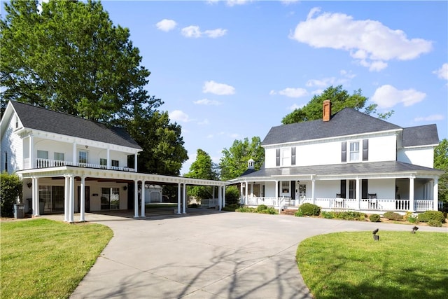 farmhouse-style home with driveway, a porch, a front lawn, and a chimney