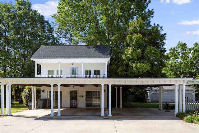 view of front facade featuring concrete driveway, an attached carport, and roof with shingles