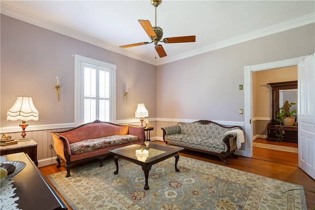 living room featuring a wainscoted wall, ceiling fan, wood finished floors, and crown molding