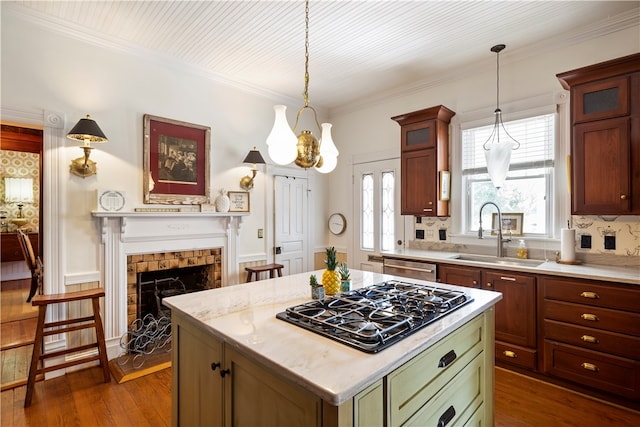 kitchen with black gas cooktop, a sink, a tiled fireplace, dark wood finished floors, and decorative light fixtures