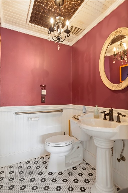 half bath featuring a chandelier, crown molding, and wainscoting