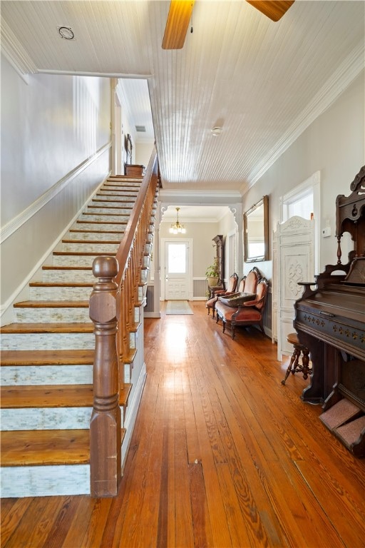 stairway featuring ornamental molding, ceiling fan with notable chandelier, wood ceiling, and hardwood / wood-style flooring