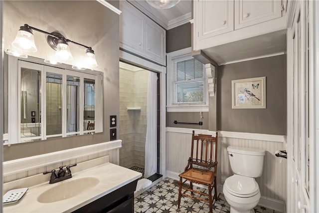 full bath featuring toilet, a wainscoted wall, a tile shower, crown molding, and vanity