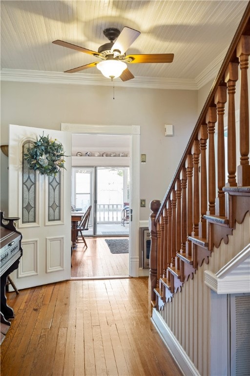 foyer featuring stairs, hardwood / wood-style floors, a ceiling fan, and crown molding