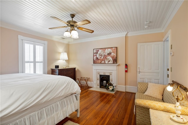 bedroom with crown molding, ceiling fan, wood finished floors, a tile fireplace, and baseboards