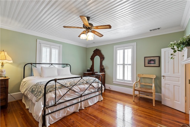 bedroom with hardwood / wood-style floors, multiple windows, and visible vents