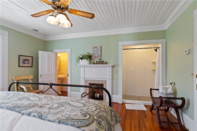 bedroom featuring visible vents, baseboards, wood finished floors, crown molding, and a brick fireplace